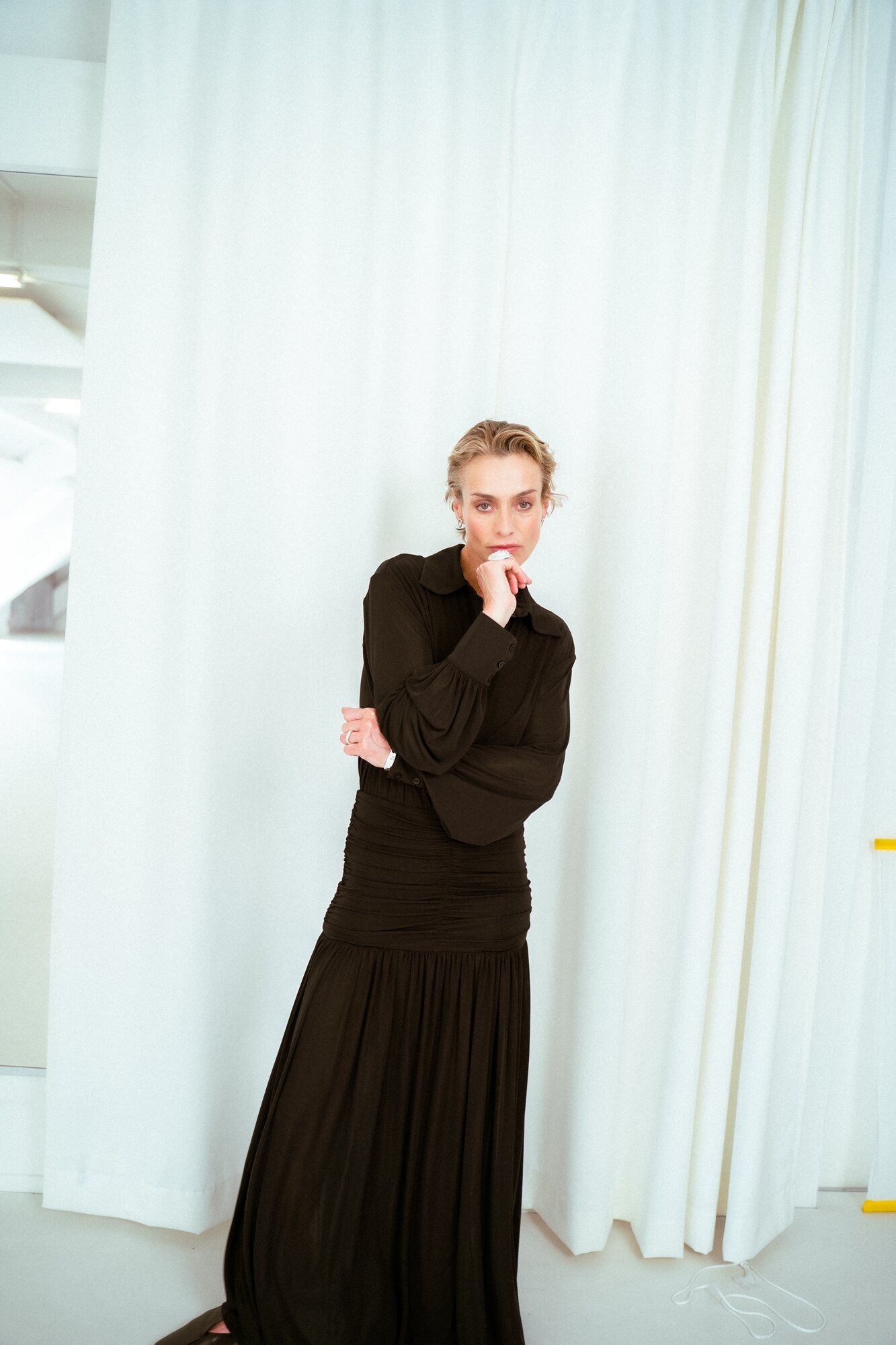 Editorial: Model in schwarzem Kleid vor weißen Vorhängen